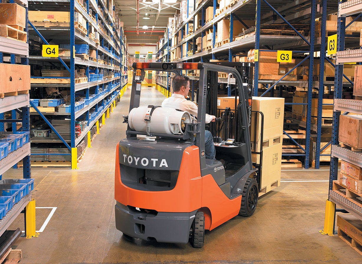 Man driving a Toyota IC cushion forklift in a warehouse